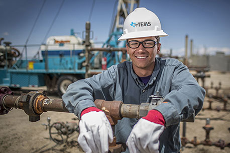 Smiling worker in hard hat and safety glasses holding industrial equipment