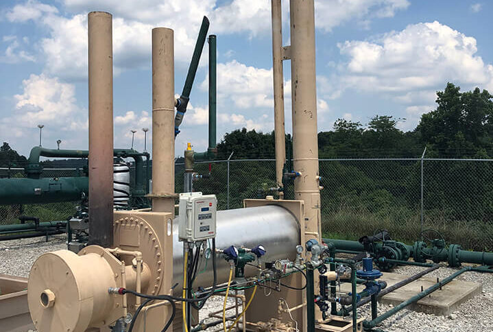 Outdoor industrial setup with tall stacks and machinery, under a partly cloudy sky