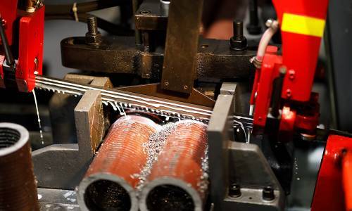 Close-up of a pipe cutting process with machinery in an industrial setting